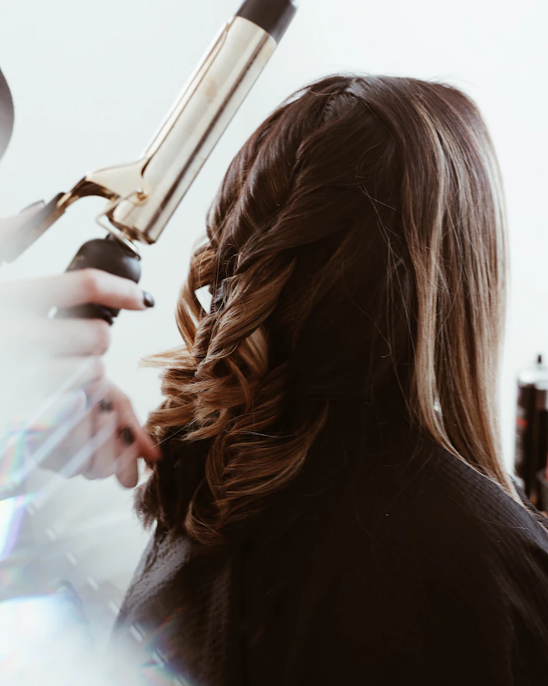 Student curling a model's hair with a curling tong, Finenticee hair styling class, Bhubaneswar