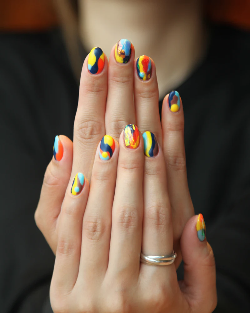 Student building a nail extension on a model's hand in the Finenticee classroom